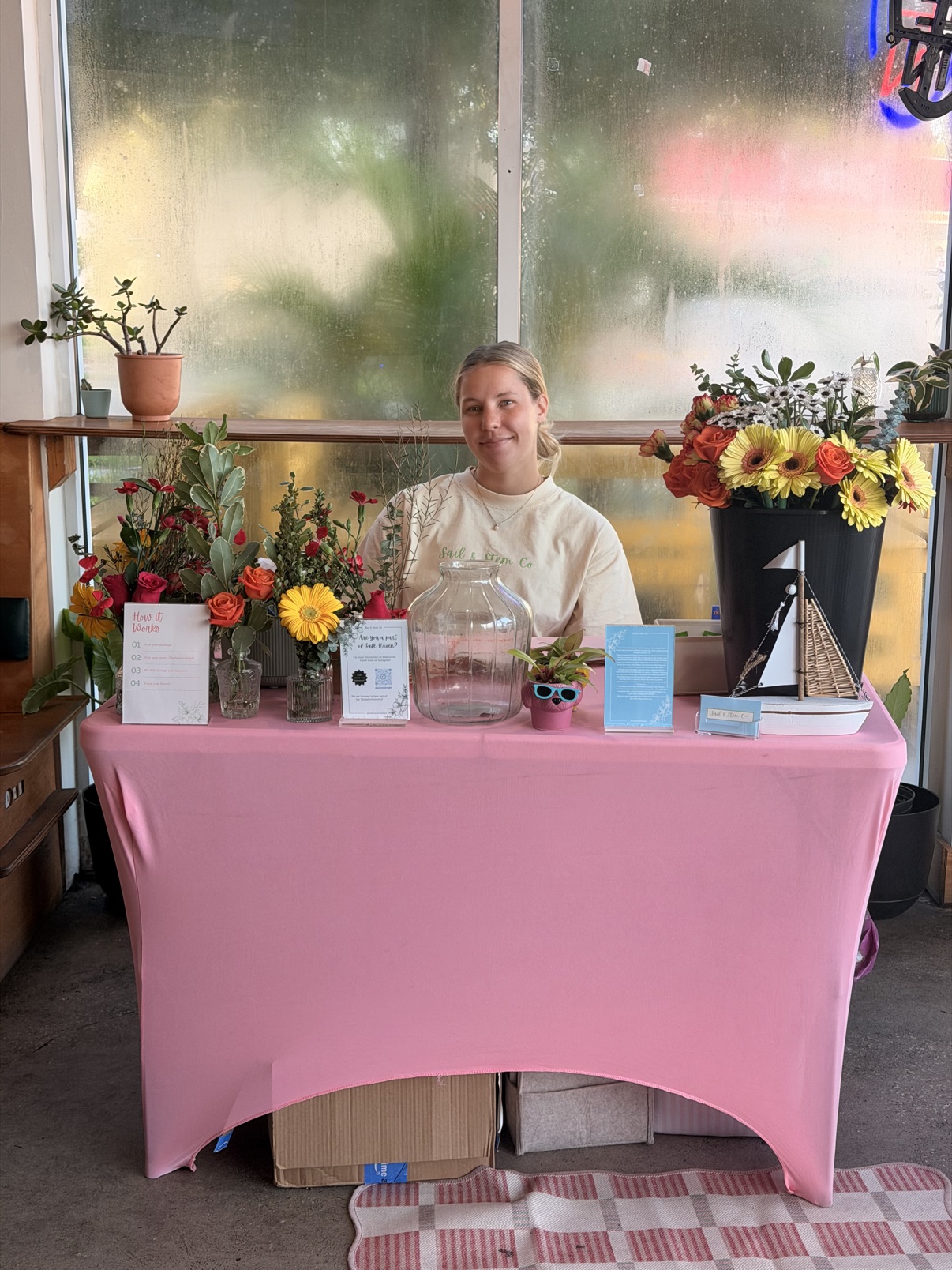 Florist standing behind a pink bloom bar table with fresh flowers