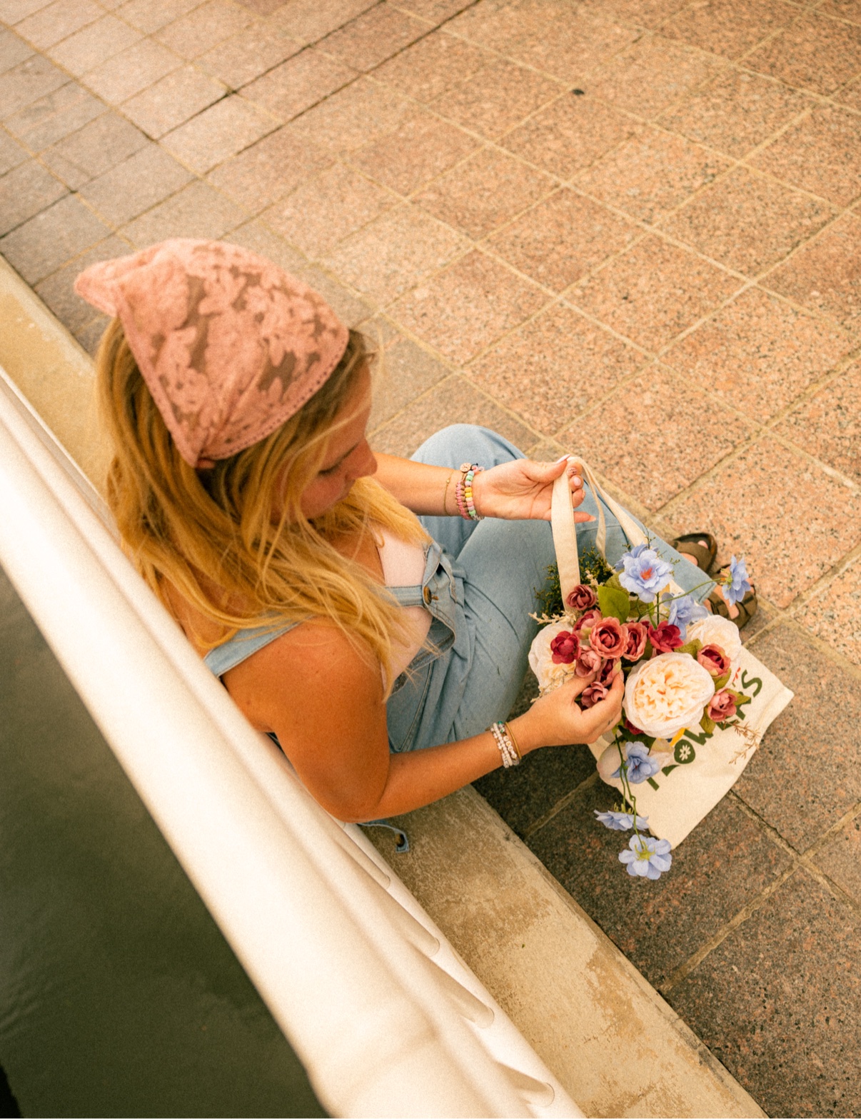 Overhead view of Kai arranging blooms spilling out of her flower tote
