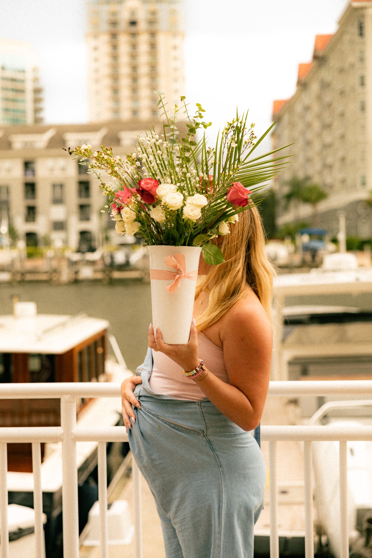 Kai holding a large bouquet of roses and greenery up to her face