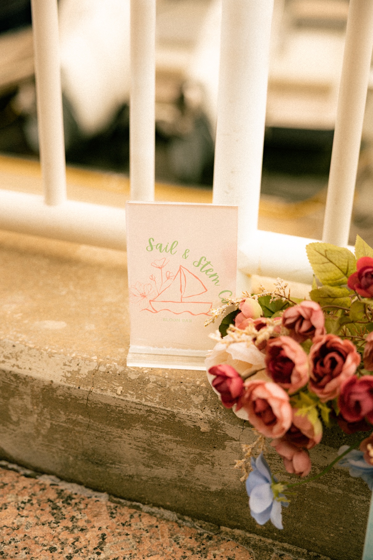 A handwritten card resting beside a fresh bouquet on the steps