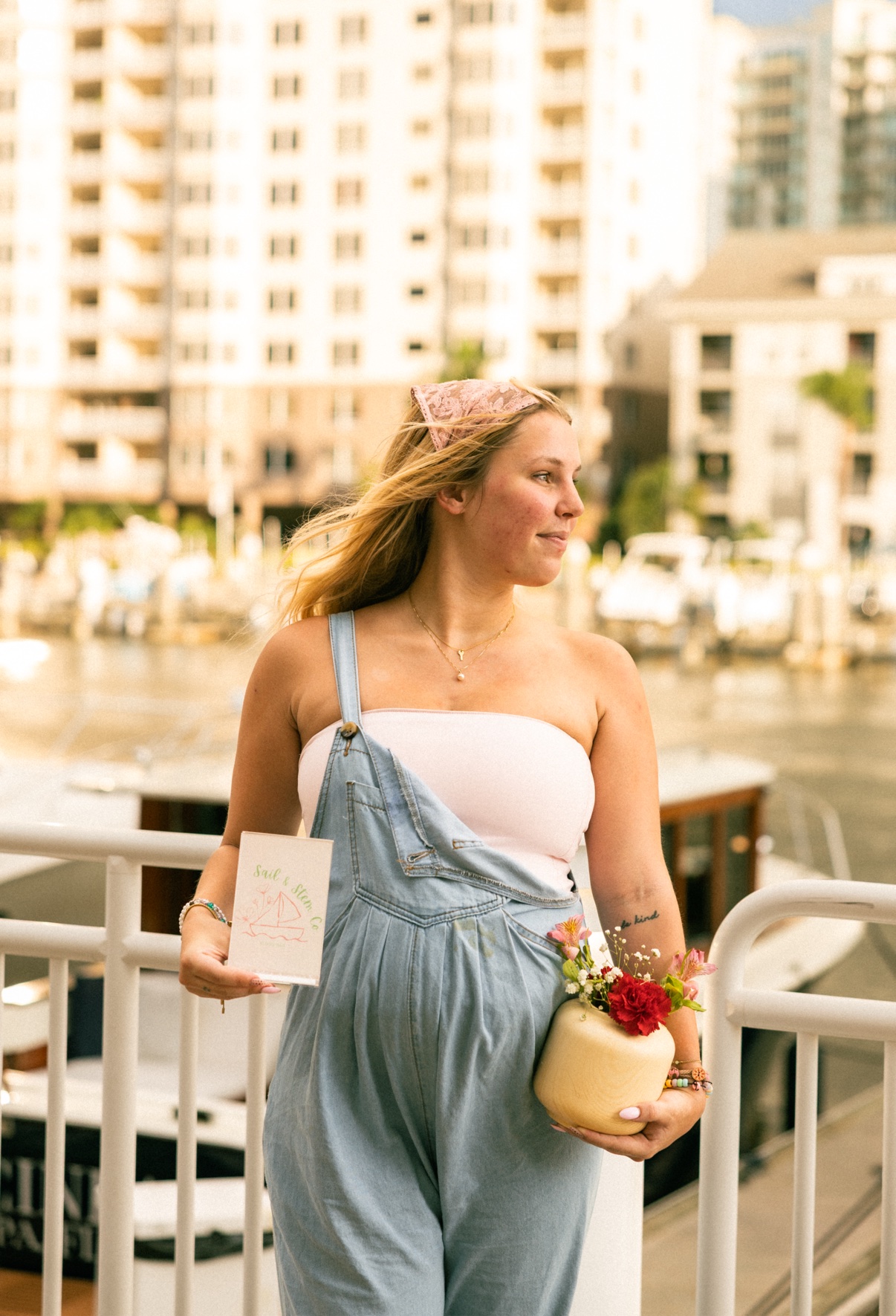Kai holding a small jar arrangement beside a waterfront railing