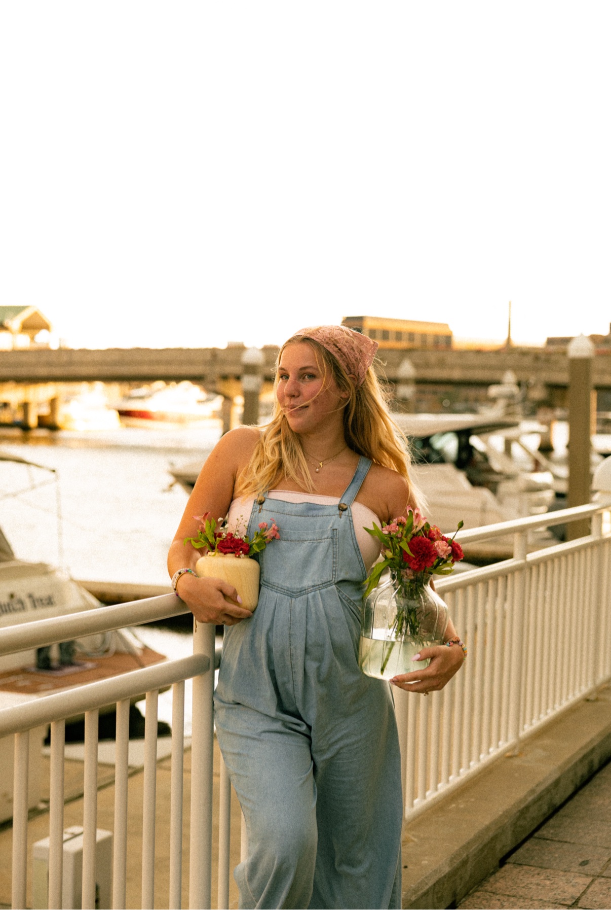 Kai holding a glass vase arrangement beside a waterfront railing