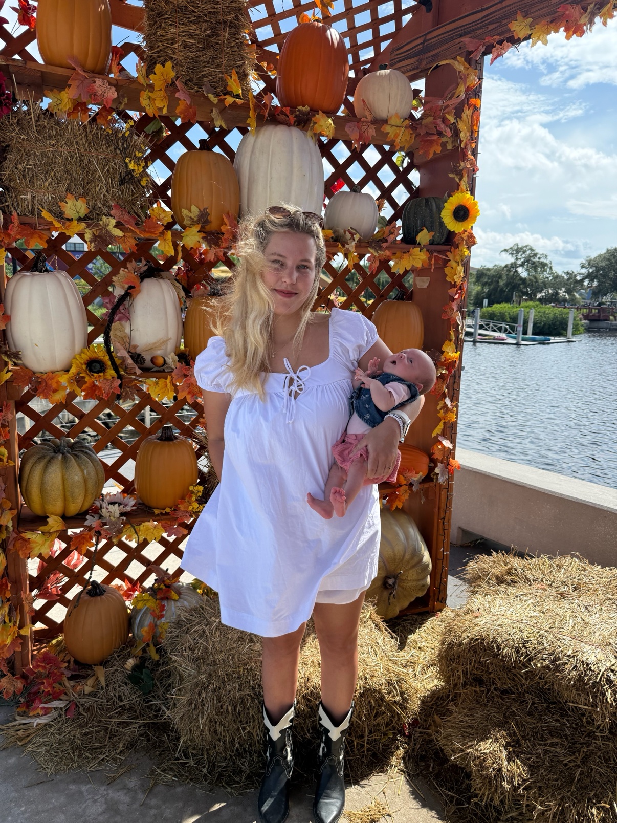 Kai holding her newborn daughter at a fall pumpkin display