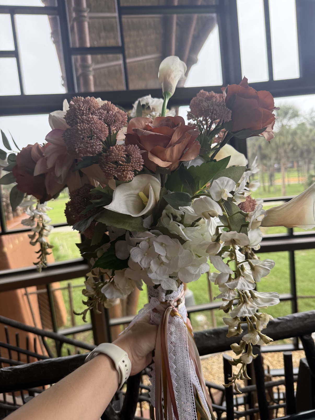 Hand holding the custom faux Victorian Grande bouquet with lace and ribbon streamers at Disney's Animal Kingdom Lodge