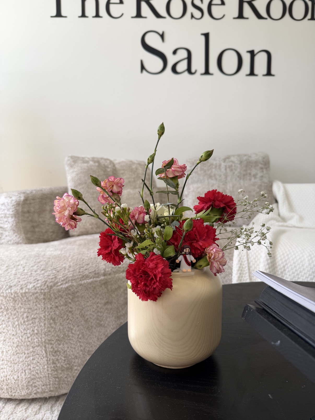 Pink and red carnations arranged in a cream vase at a salon event